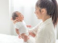 A beautiful Asian woman is looking at her newborn baby with happiness and love