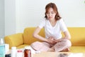 Beautiful Asian woman with lower abdominal pain. She sits on the sofa at home.