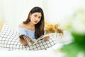 Beautiful Asian woman lying on white cozy bed reading a book enjoys of rest at comfort home Royalty Free Stock Photo