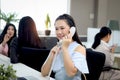 Beautiful Asian woman officer talking with customer by using landline phone at working desk in office with blurred background of Royalty Free Stock Photo