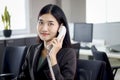 Beautiful Asian woman operator officer talking with customer by using landline phone at working desk in office with busy working Royalty Free Stock Photo
