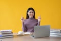 A beautiful Asian woman is pointing her finger up, smiling and looking at the camera Royalty Free Stock Photo