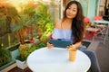 Beautiful asian woman reading a magazine online on tablet at coffee cafe. Royalty Free Stock Photo