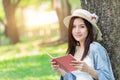 Beautiful Asian woman reading pink book in the park