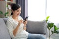 Beautiful Asian woman relaxing on comfortable sofa, enjoying web surfing information in internet or using mobile software Royalty Free Stock Photo