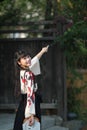 A beautiful Asian woman in retro Japanese style dress walking in a garden and smiling Royalty Free Stock Photo