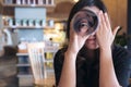 A beautiful Asian woman roll a book and looking through it with one eye while closing another eye with feeling happy