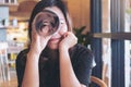 A beautiful Asian woman roll a book and looking through to a photographer with feeling happy