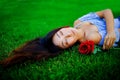 Beautiful asian woman with rose in nature. Beauty woman with long hair relax on green grass. Royalty Free Stock Photo