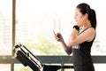Beautiful asian woman running treadmill use smartphone listening Royalty Free Stock Photo
