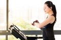 Beautiful asian woman running treadmill use smartwatch listening Royalty Free Stock Photo