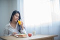 Beautiful asian woman savored the tangy and refreshing taste of the orange juice as she ate her breakfast