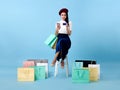 Beautiful Asian woman shopper sitting and carrying shopping bags with using credit card and mobile phone in hands on blue Royalty Free Stock Photo