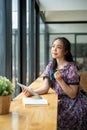 A beautiful Asian woman is sipping coffee and daydreaming while sitting in a coffee shop Royalty Free Stock Photo