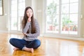 Beautiful Asian woman sitting barefoot on the floor at home with hand on chin thinking about question, pensive expression