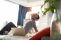 Beautiful Asian woman sitting on bed, resting after working from home on laptop Royalty Free Stock Photo