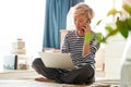 Beautiful Asian woman sitting on bed & working from home on laptop Royalty Free Stock Photo