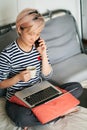 Beautiful Asian woman sitting on bed & working from home on laptop Royalty Free Stock Photo