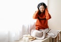 Beautiful Asian woman sitting in comfortable windowsill in winter morning enjoy listen music with eyes closed relaxing in cozy Royalty Free Stock Photo