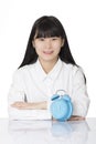 Asian woman sitting at desk smiling with clock on white backgro Royalty Free Stock Photo