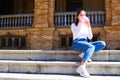 Beautiful asian woman sitting on the stairs of a square filling a pink balloon with air to give to a little boy