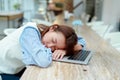 A beautiful Asian woman sleeps in front of a laptop computer in a bakery