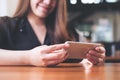 A beautiful Asian woman with smiley face holding and using horizontal smart phone to watching tv and playing games Royalty Free Stock Photo