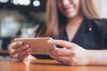 A beautiful Asian woman with smiley face holding and using horizontal smart phone to watching tv and playing games Royalty Free Stock Photo