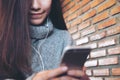 A beautiful Asian woman with smiley face holding , using and looking at smart phone in modern cafe Royalty Free Stock Photo