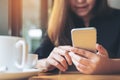 A beautiful Asian woman with smiley face holding and using smart phone with coffee cup on wooden table Royalty Free Stock Photo