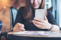 A beautiful Asian woman with smiley face holding and using smart phone with magazines Royalty Free Stock Photo