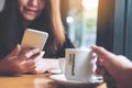 A beautiful Asian woman with smiley face using and looking at smart phone in the cafe Royalty Free Stock Photo