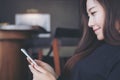 A beautiful Asian woman with smiley face using and looking at smart phone in modern cafe Royalty Free Stock Photo