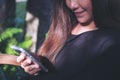 A beautiful Asian woman with smiley face using and looking at smart phone in modern cafe Royalty Free Stock Photo