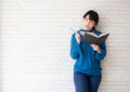 Beautiful asian woman smiling standing thinking and writing notebook on concrete cement white background