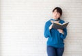 Beautiful asian woman smiling standing thinking and writing notebook on concrete cement white background.