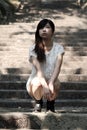 Beautiful Asian woman squatting on cement steps