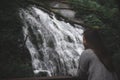 A beautiful Asian woman standing in front of waterfall in tropical forest Royalty Free Stock Photo