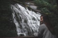 A beautiful Asian woman standing in front of waterfall in tropical forest Royalty Free Stock Photo