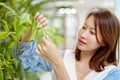 A beautiful Asian woman is standing in the garden plucking leaves happily and smiling