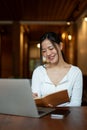 A beautiful Asian woman is studying online or working remotely at a coffee shop Royalty Free Stock Photo