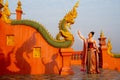 Beautiful Asian woman with Thai traditional dress stand with action of Thai dance in front of the naga sculpture in temple area