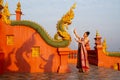 Beautiful Asian woman with Thai traditional dress stand with action of Thai dance in front of the naga sculpture in temple area