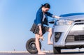 Beautiful asian woman treading on wrench while changing flat tire wheel