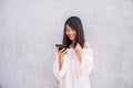 Beautiful asian woman using cellphone over concrete wall Royalty Free Stock Photo