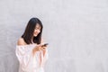 Beautiful asian woman using cellphone over on concrete wall Royalty Free Stock Photo