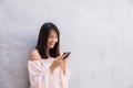 Beautiful asian woman using cellphone, over concrete wall Royalty Free Stock Photo