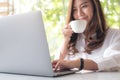 A beautiful Asian woman using laptop while drinking coffee in cafe Royalty Free Stock Photo