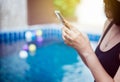 Beautiful asian woman using mobile phone at swimming pool,Happy and smiling,Relax time,Summer travel concept Royalty Free Stock Photo