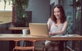 Beautiful Asian woman wearing casual clothes, typing, chatting and working outside at cafe, using laptop, smiling with happiness Royalty Free Stock Photo